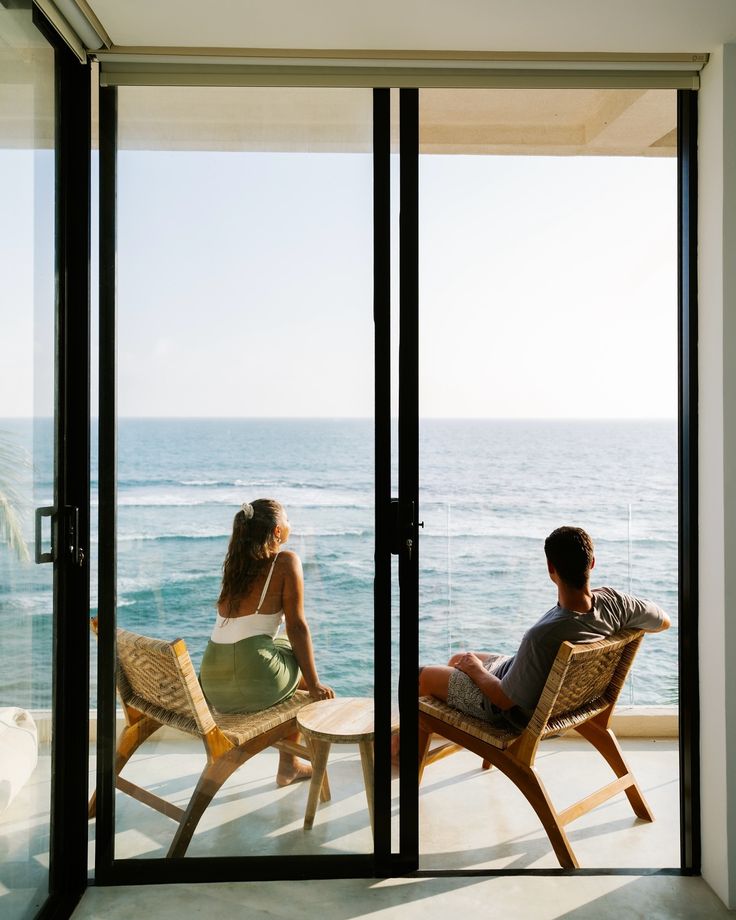 Two guests seated by open doors overlooking the sea
